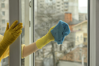 Woman cleaning window at home, closeup view