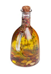 Photo of Glass jug of cooking oil with spices and herbs isolated on white