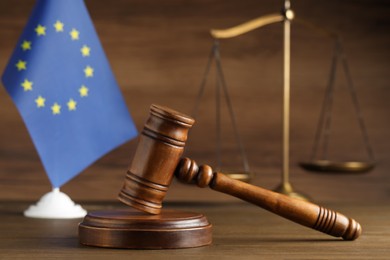 Photo of Judge's gavel, scales of justice and European Union flag on wooden table