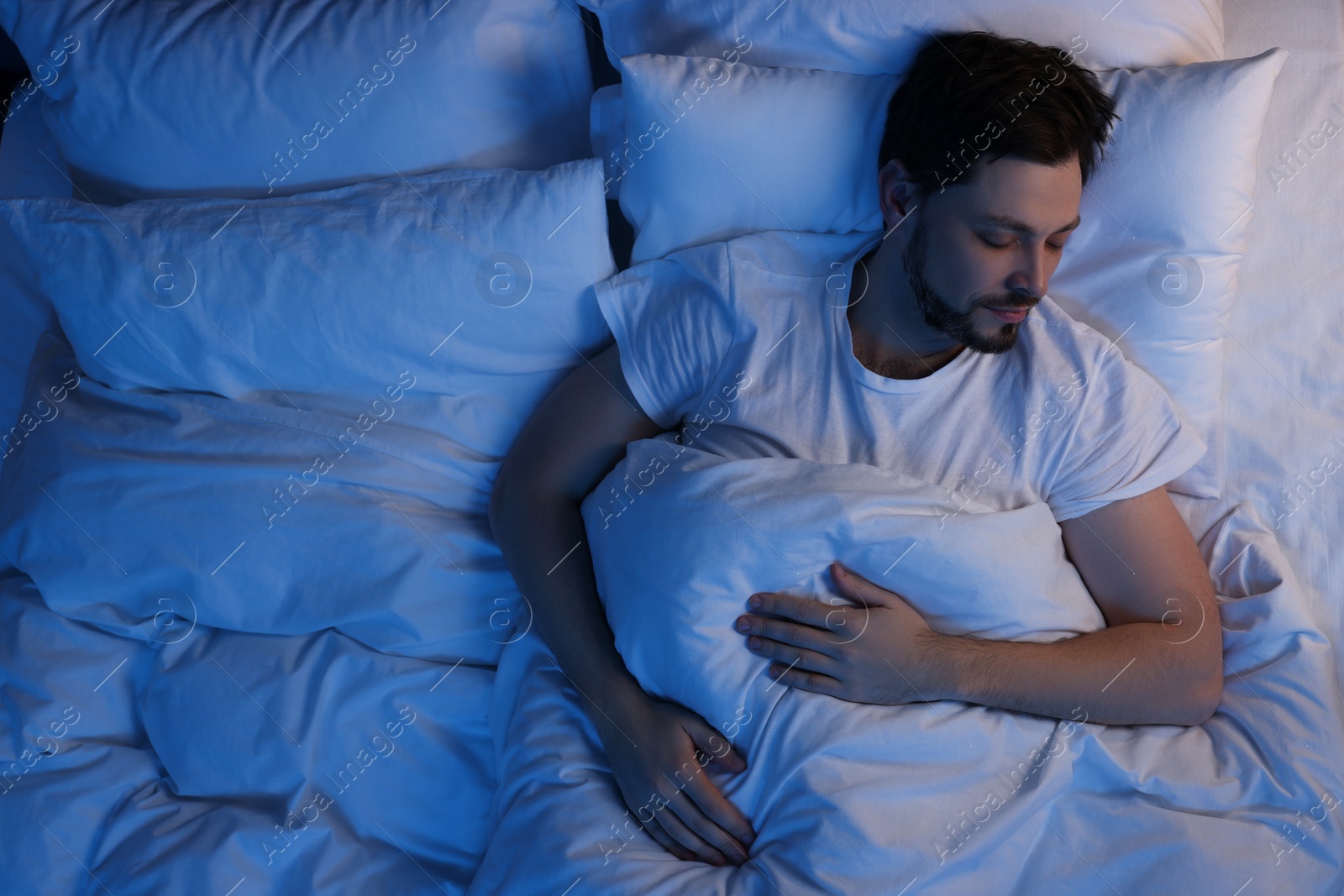 Photo of Man sleeping in bed at night, above view. Space for text