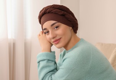 Photo of Cancer patient. Young woman with headscarf near window indoors