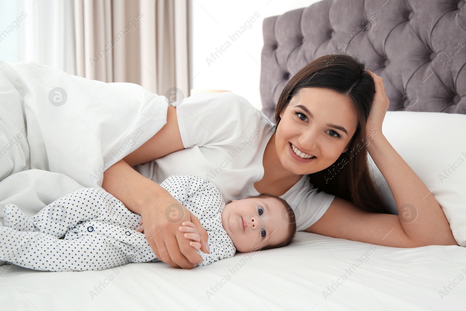 Photo of Happy woman with her cute baby on bed