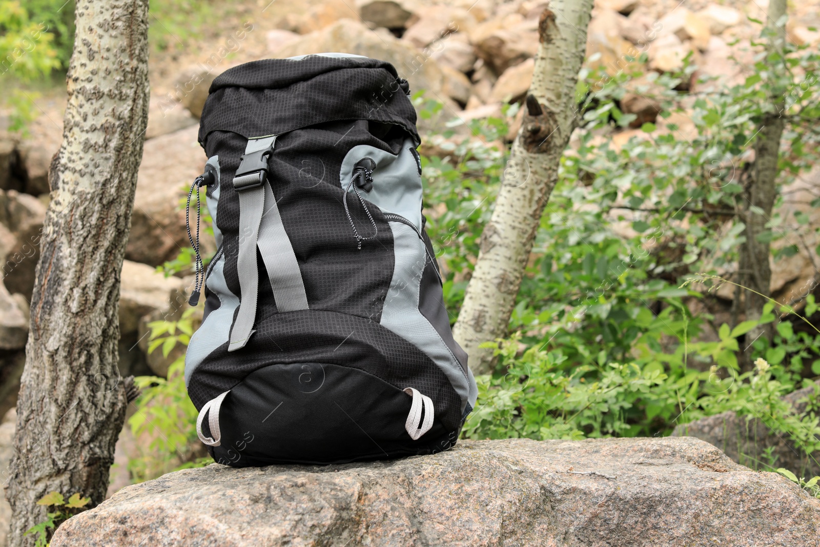 Photo of Large camping backpack on stone in forest. Space for text