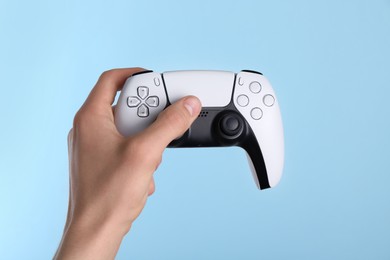 Photo of Man using wireless game controller on light blue background, closeup