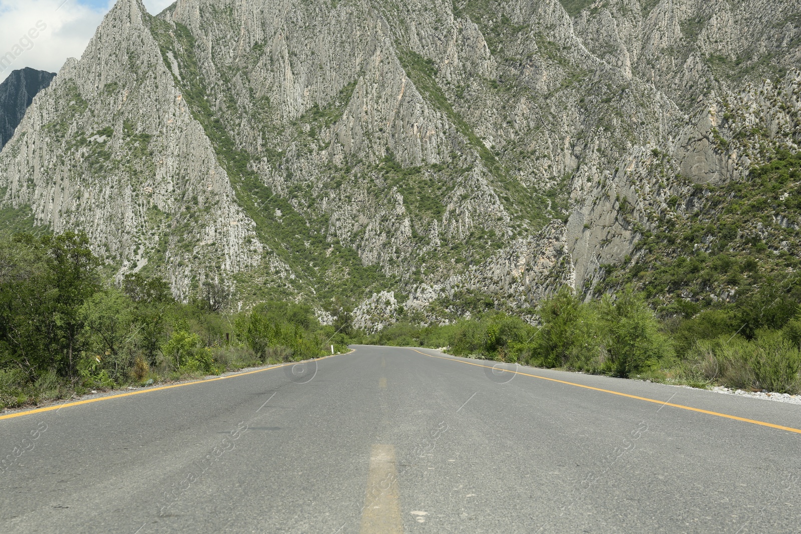 Photo of Picturesque view of big mountains and bushes near road