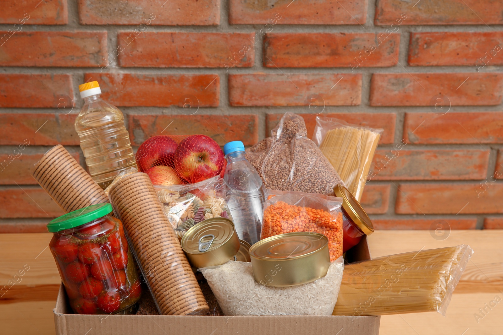 Photo of Donation box with food on table near brick wall