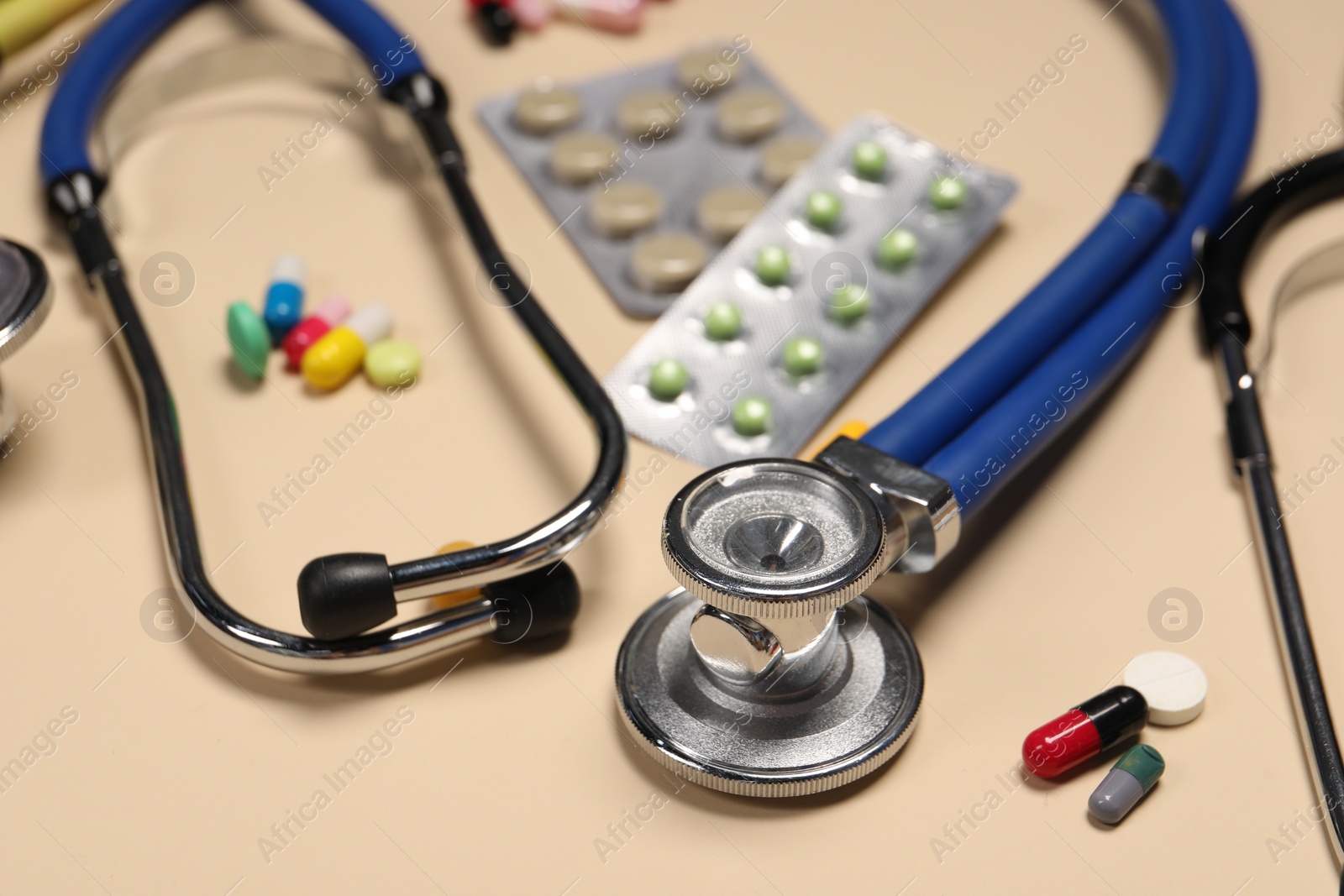 Photo of Stethoscope and pills on beige background, closeup. Medical tool