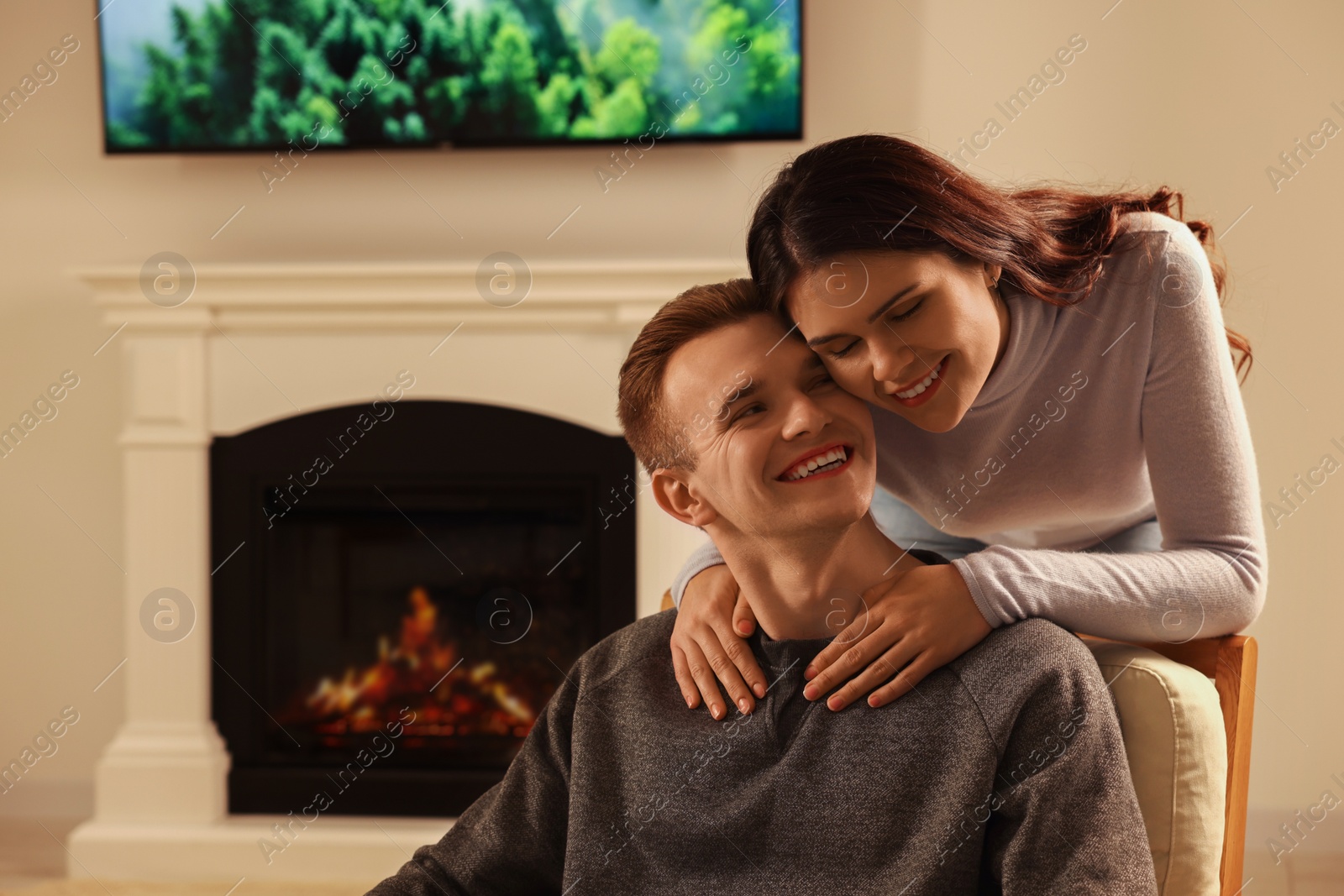 Photo of Happy lovely couple spending time together near fireplace at home