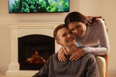 Photo of Happy lovely couple spending time together near fireplace at home