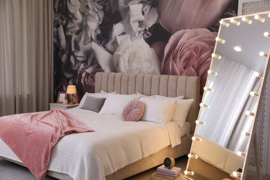 Photo of Beautiful room interior with large bed, mirror and floral pattern on wall