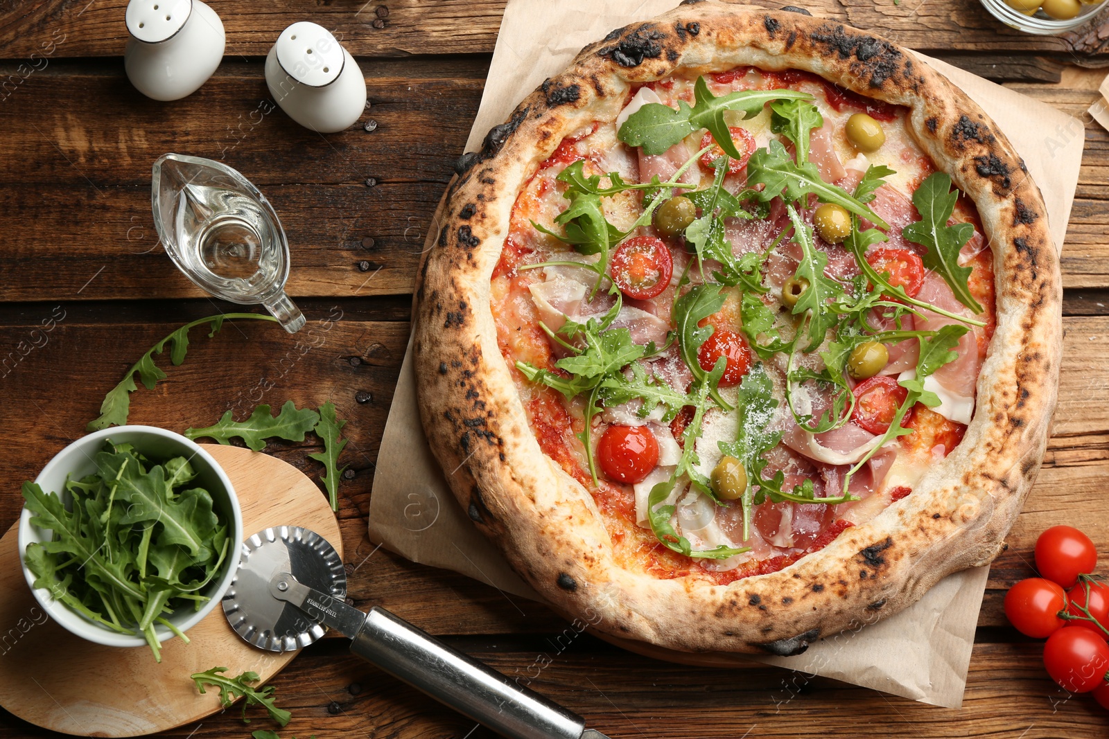 Photo of Tasty pizza with meat and arugula on wooden table, flat lay