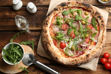 Photo of Tasty pizza with meat and arugula on wooden table, flat lay