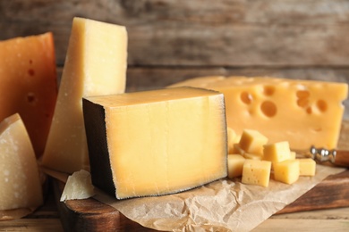 Different types of delicious cheese on table against wooden background