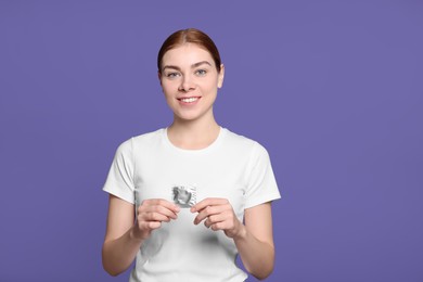 Photo of Woman holding condom on purple background. Safe sex