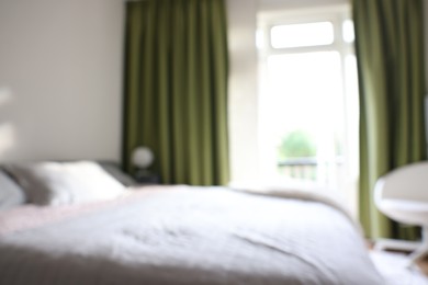 Photo of Blurred view of large bed near window in room