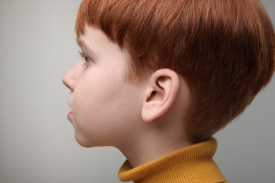 Photo of Hearing problem. Little boy on grey background. closeup