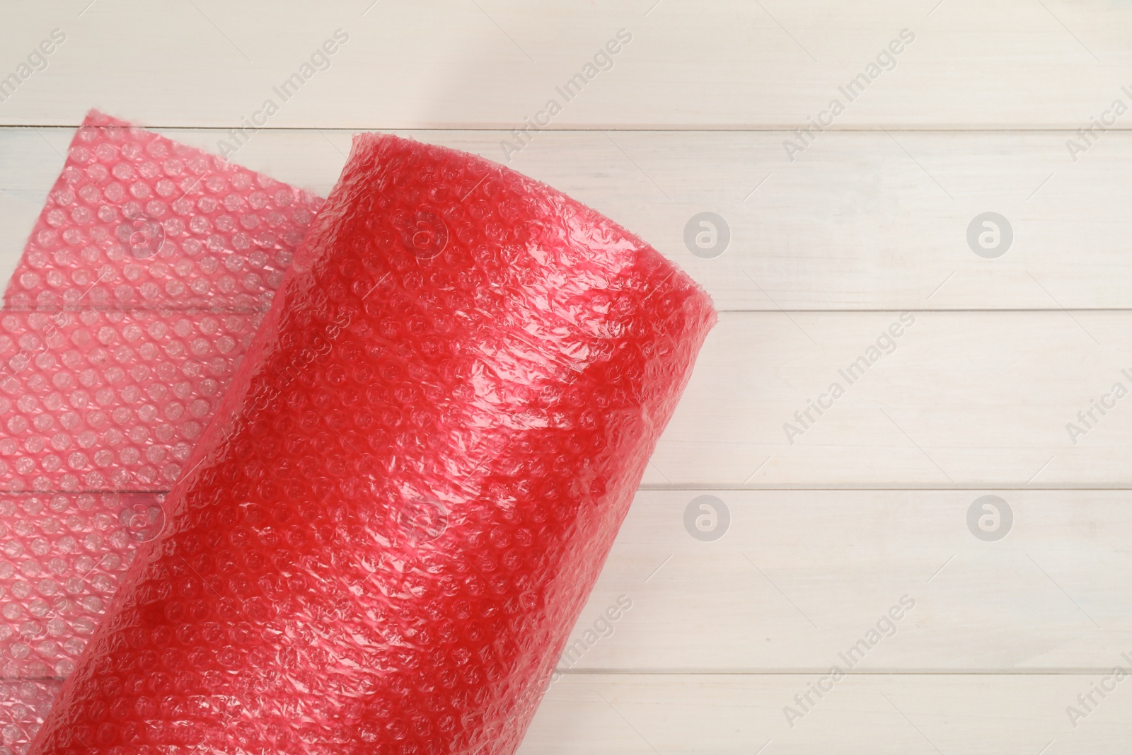 Photo of Bubble wrap roll on white wooden background, top view. Space for text