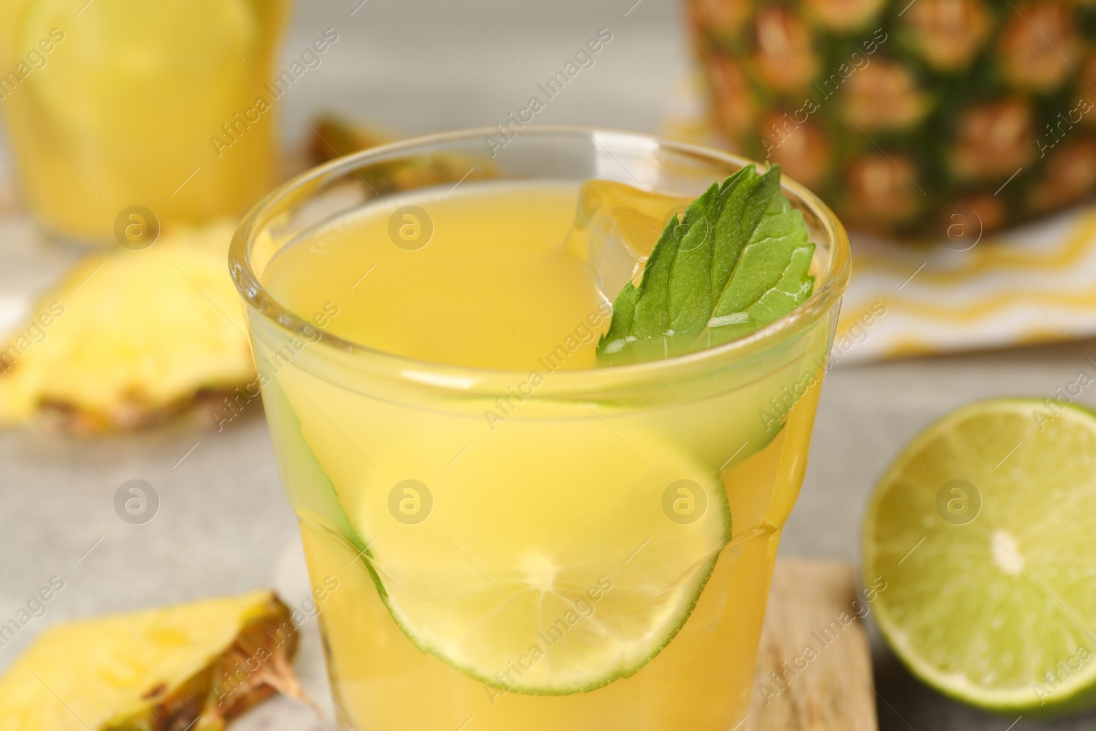 Photo of Glass of tasty pineapple cocktail with mint and lime on table, closeup