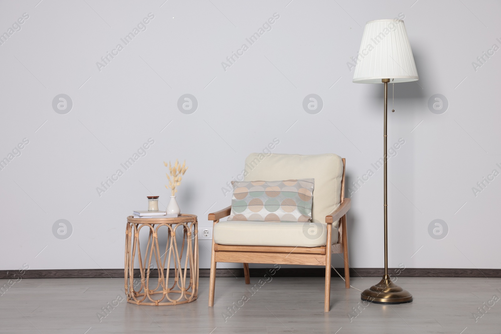 Photo of Stylish armchair, floor lamp and table near white wall. Interior design