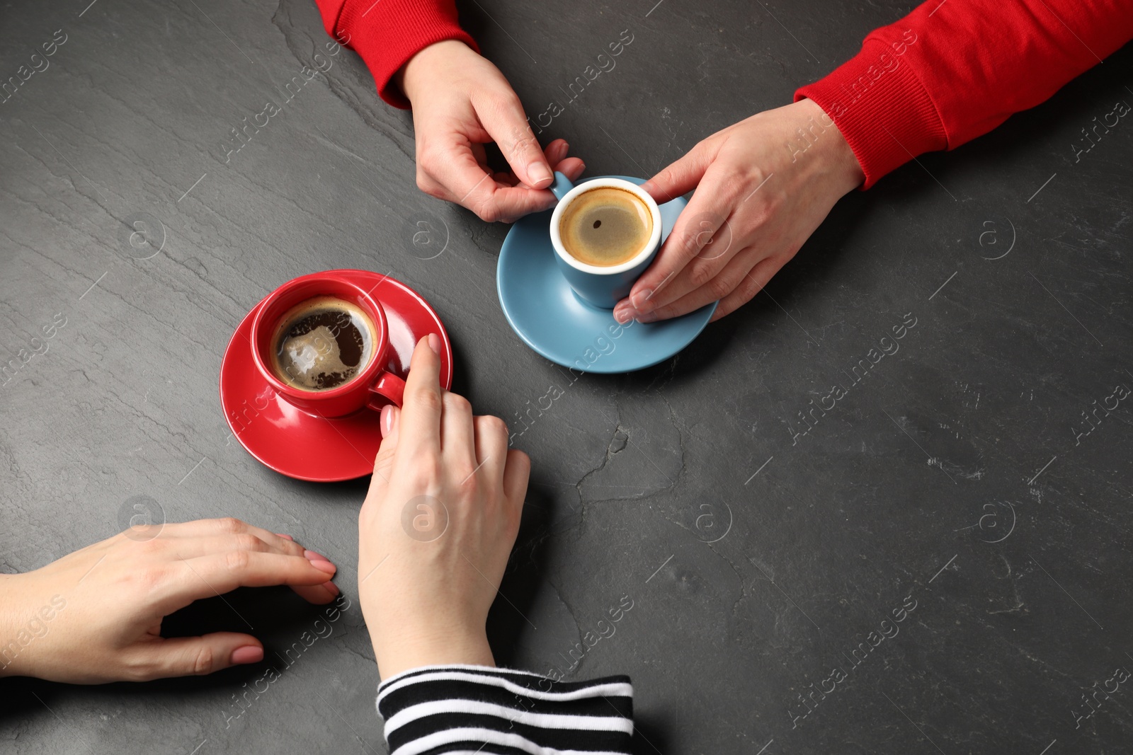 Photo of Women having coffee break at dark textured table, above view