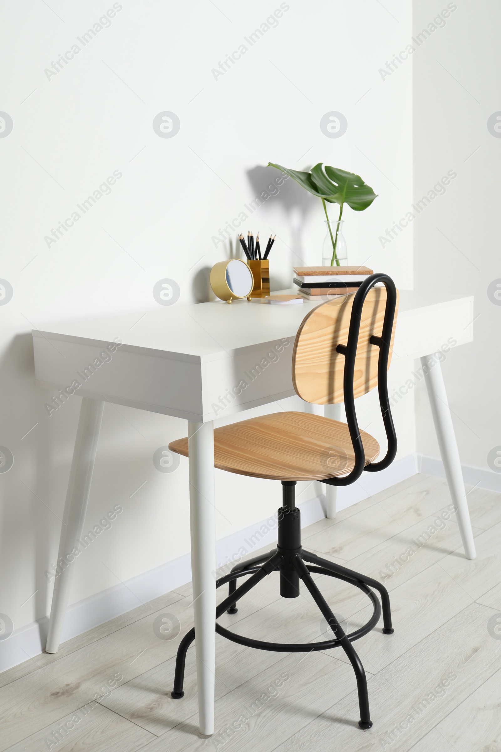 Photo of Comfortable workplace with white desk near wall indoors