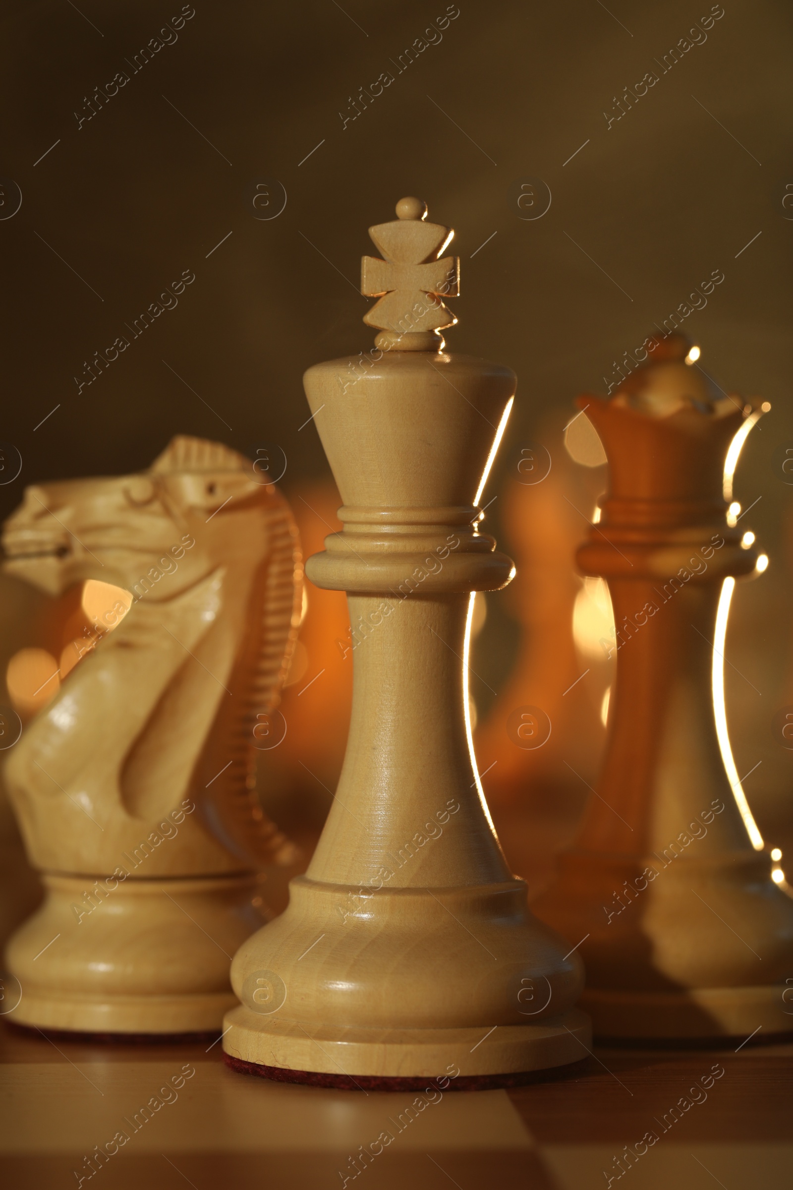 Photo of Wooden king, queen and knight on chessboard, closeup