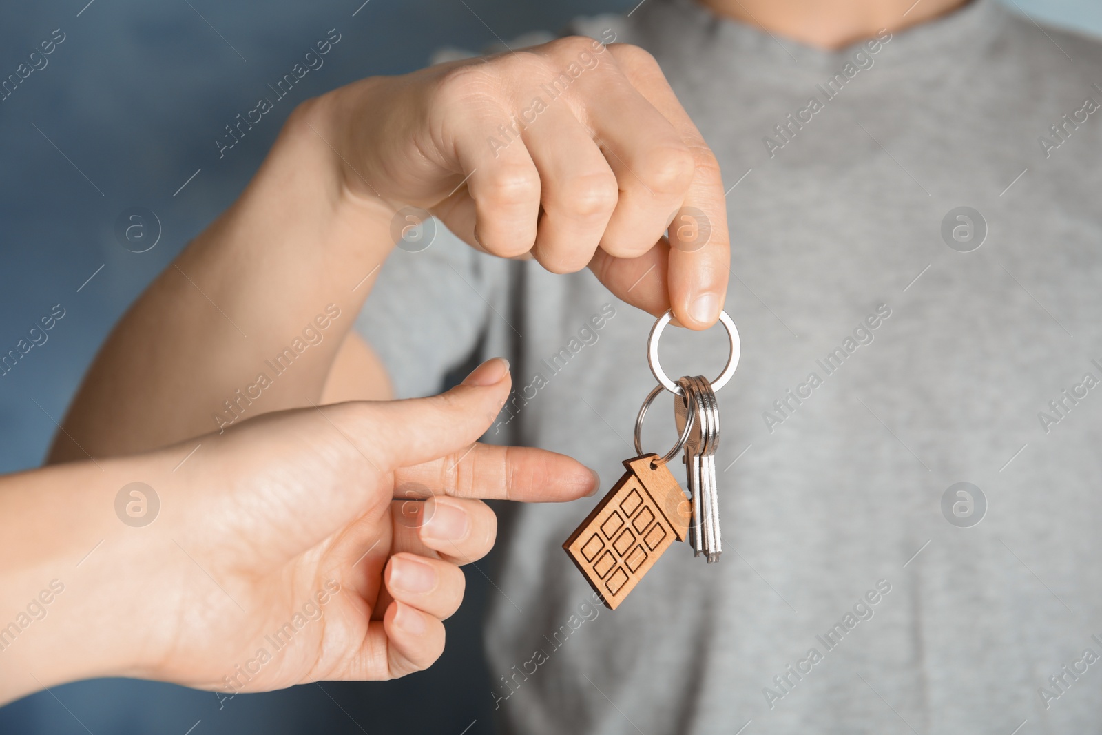 Photo of Man giving house key with trinket to woman, closeup