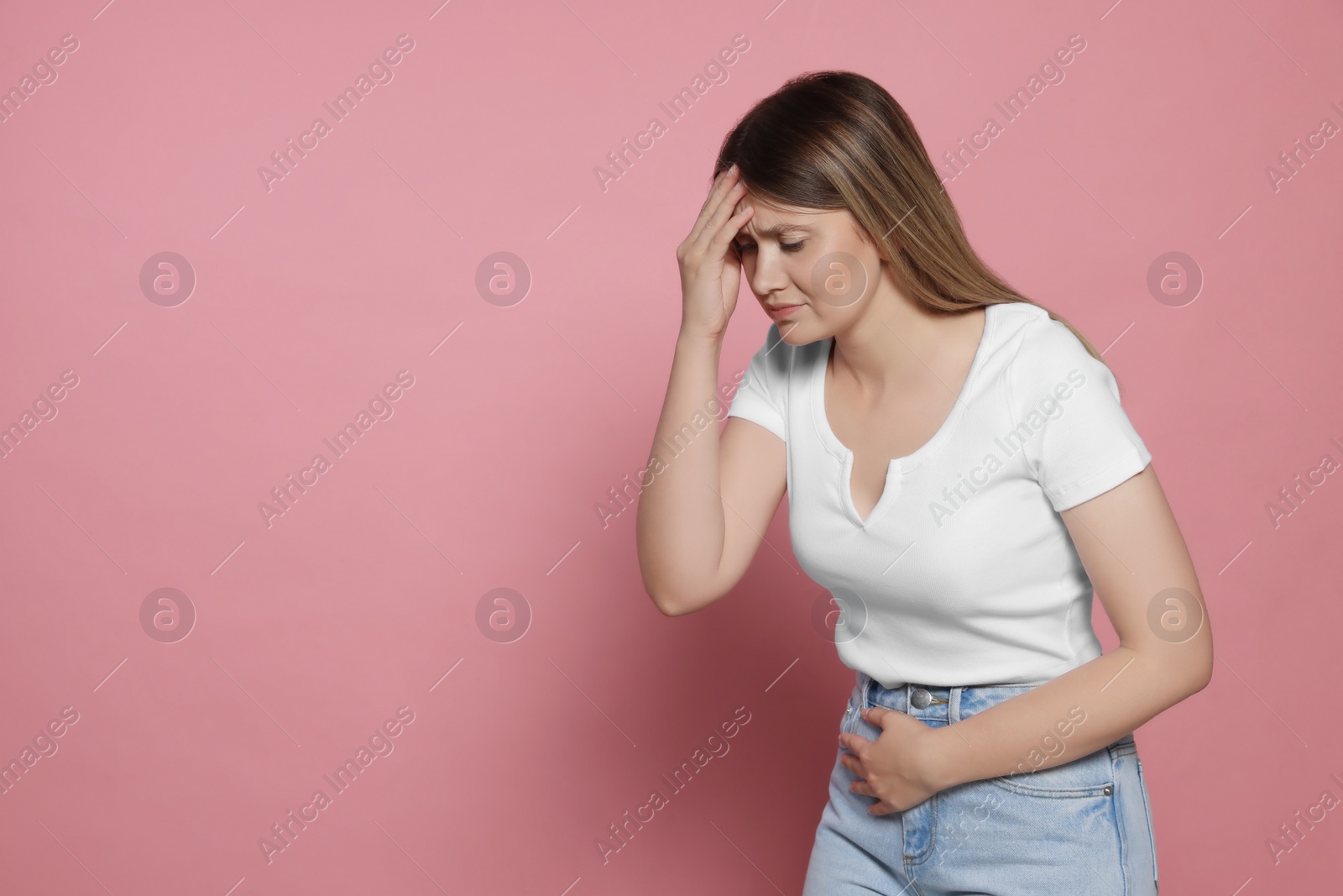 Photo of Young woman suffering from menstrual pain on pink background, space for text