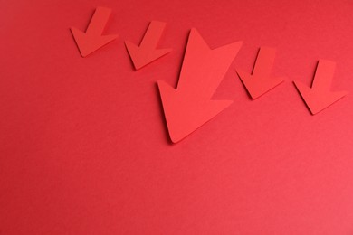 Many paper arrows on red background, above view. Space for text