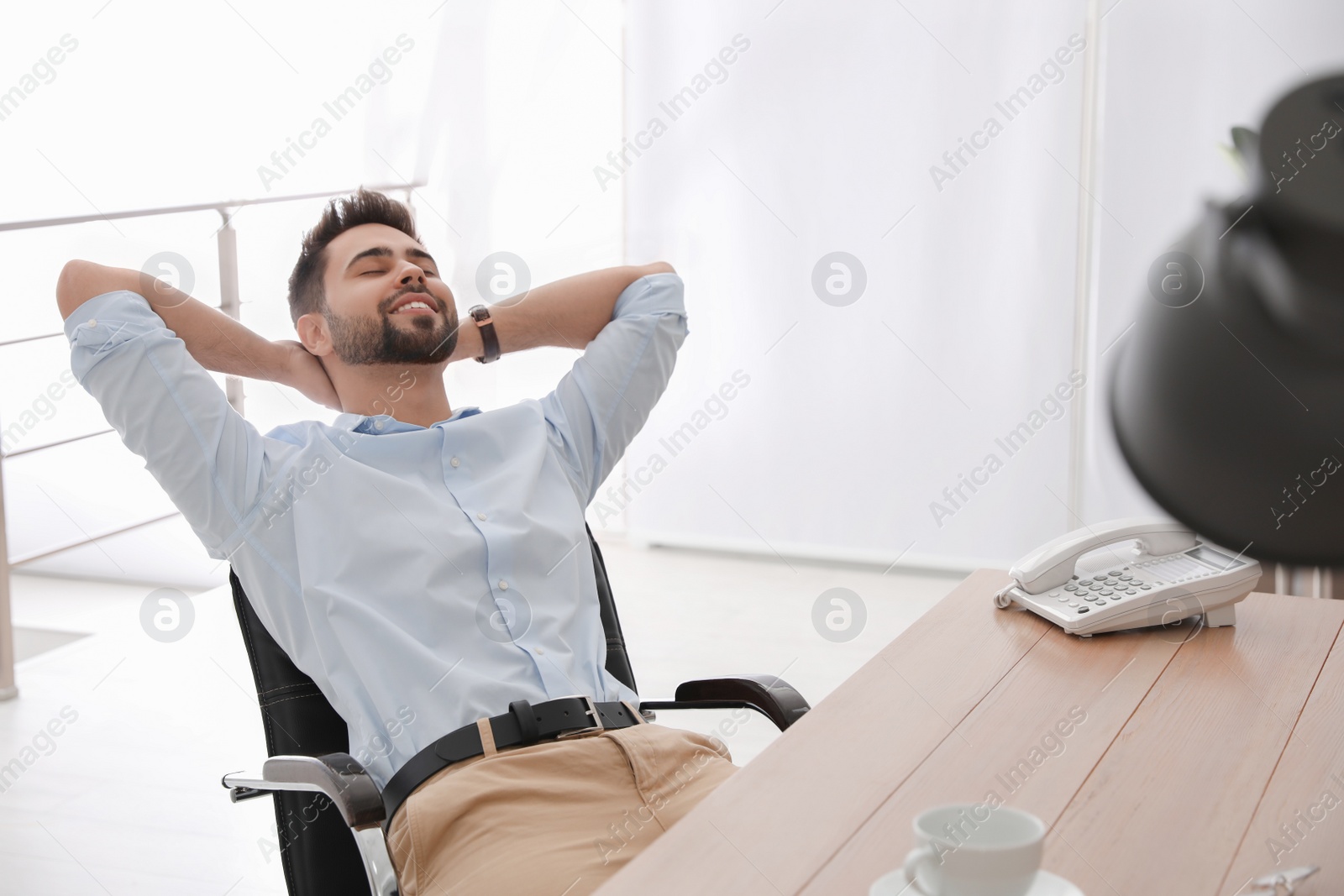 Photo of Young businessman relaxing in office chair at workplace