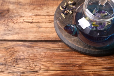 Photo of Organic blue Anchan in glass pot on wooden table, above view with space for text. Herbal tea