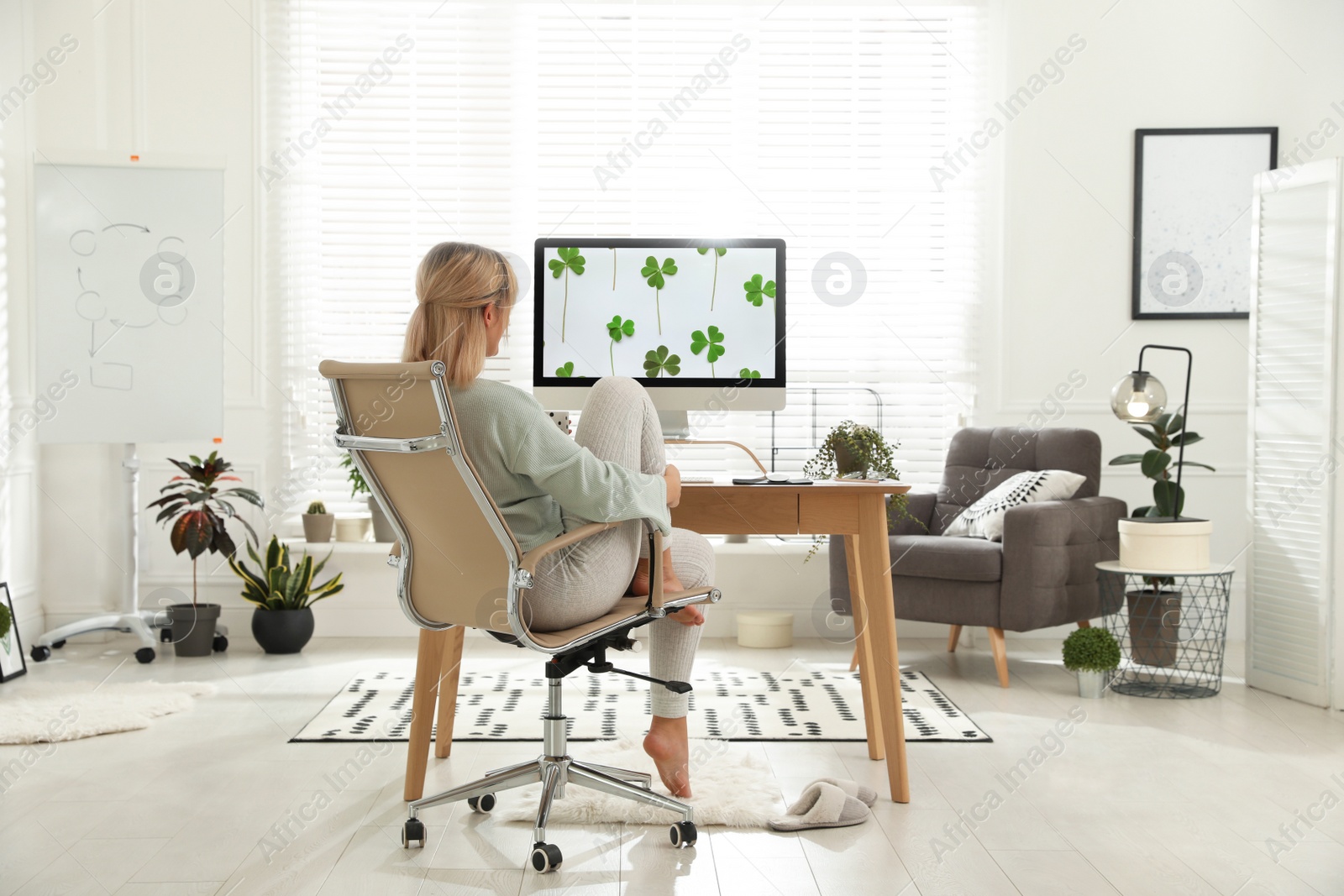 Photo of Woman with cup of tea at table in light room. Home office