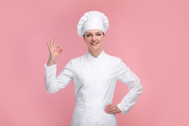 Happy chef in uniform showing OK gesture on pink background