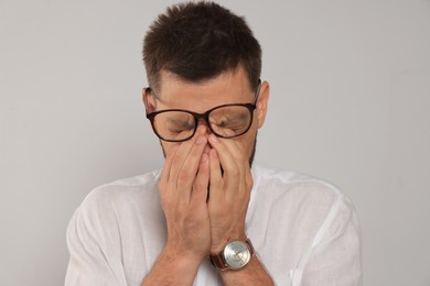 Man suffering from eyestrain on light background