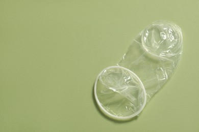 Unrolled female condom on light green background, top view and space for text. Safe sex