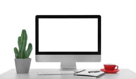 Photo of Computer, potted cactus and notebook on table against white background. Stylish workplace