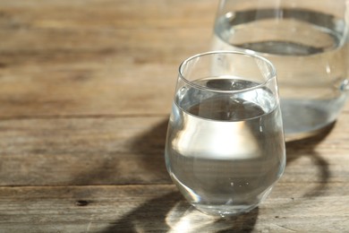 Photo of Glass of water on wooden table, space for text. Refreshing drink