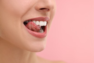 Photo of Woman with beautiful lips licking her teeth on pink background, closeup. Space for text