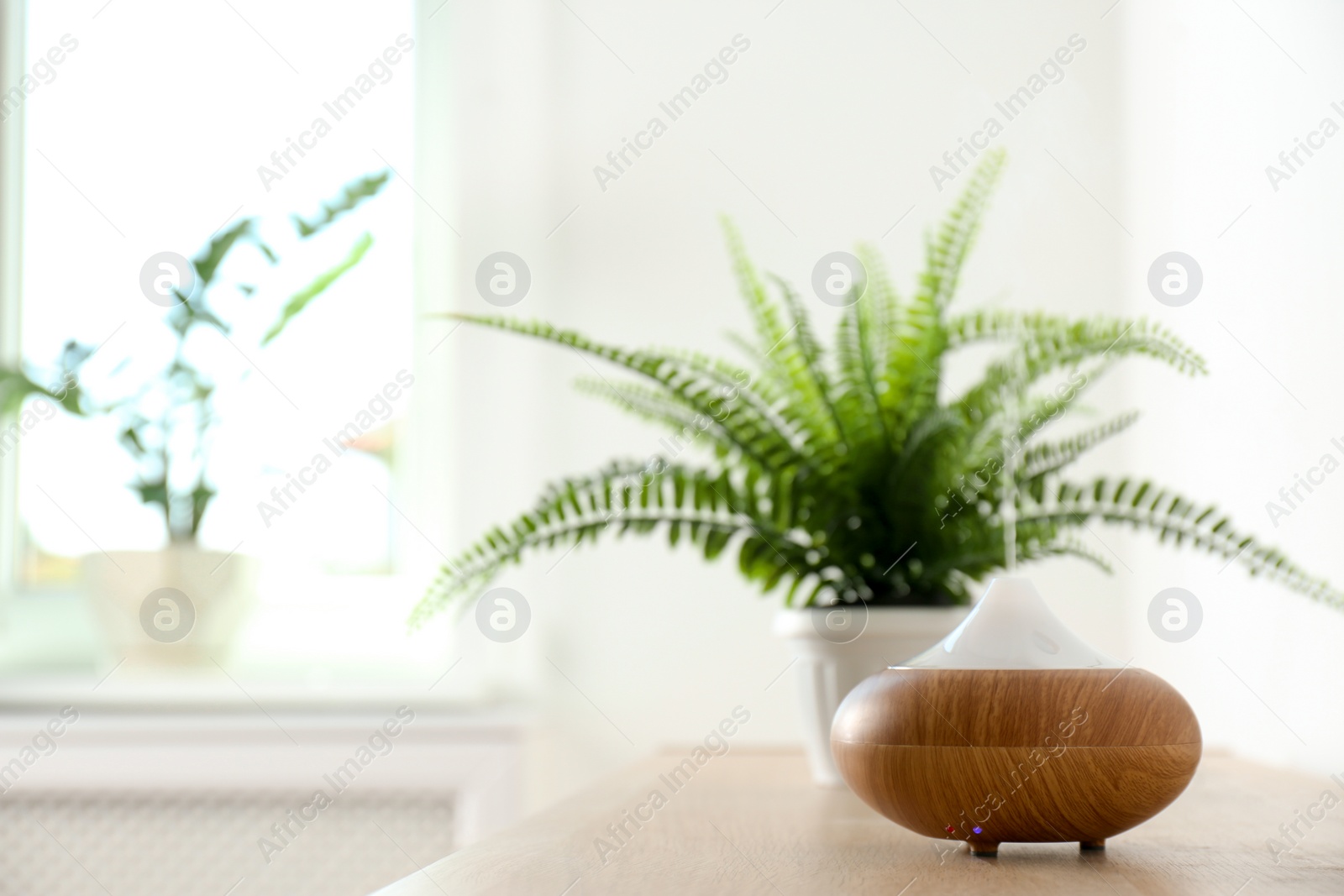 Photo of Modern aroma lamp on table against blurred background with space for text