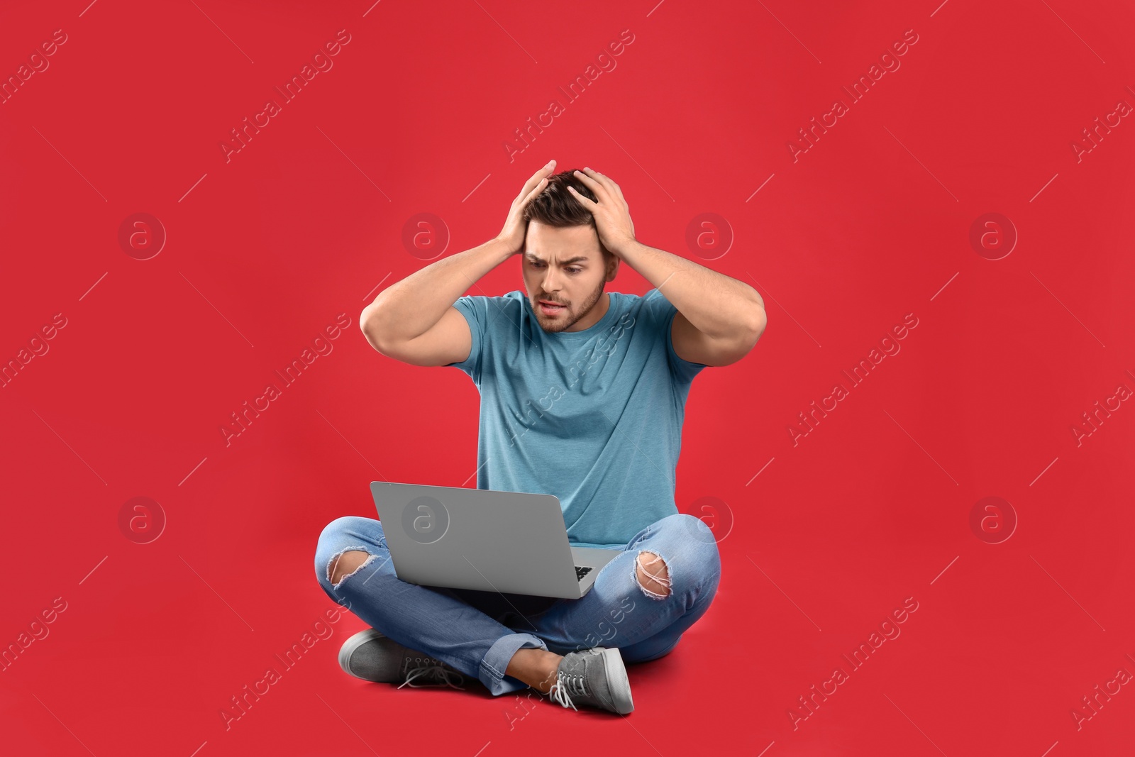 Photo of Emotional man with laptop on red background