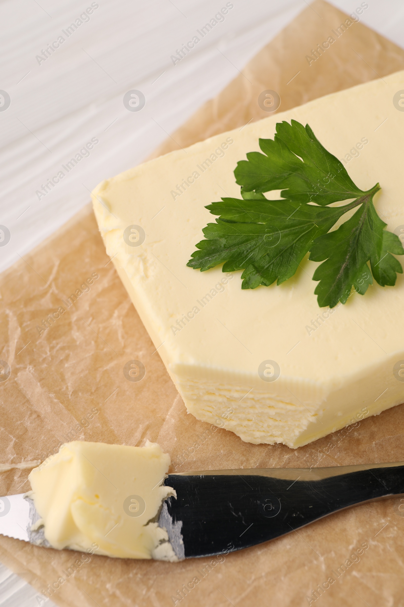 Photo of Tasty butter and knife on white wooden table, closeup