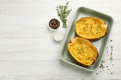 Photo of Halves of cooked spaghetti squash in baking dish, thyme and spices on white wooden table, flat lay. Space for text