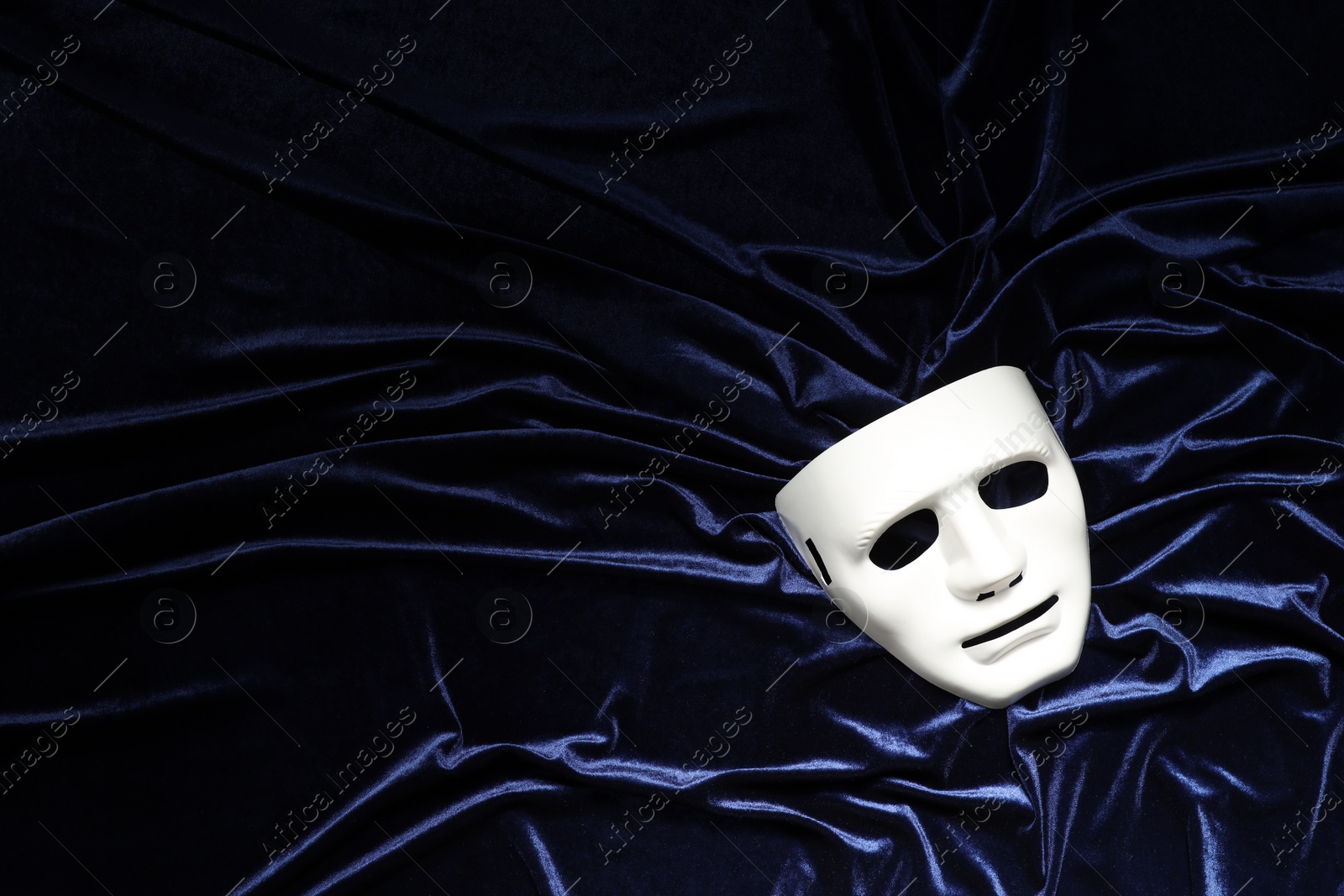 Photo of Theater arts. White mask on blue fabric, top view. Space for text