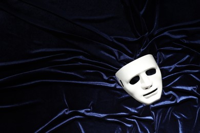 Theater arts. White mask on blue fabric, top view. Space for text