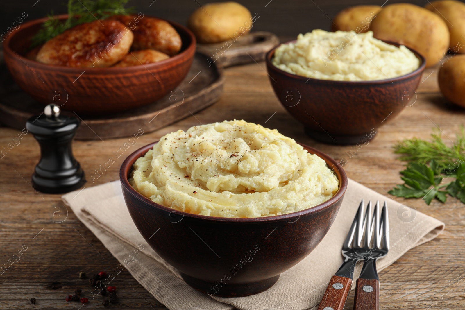 Photo of Bowl of tasty mashed potatoes with black pepper served on wooden table