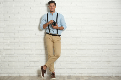 Professional photographer working near white brick wall in studio. Space for text