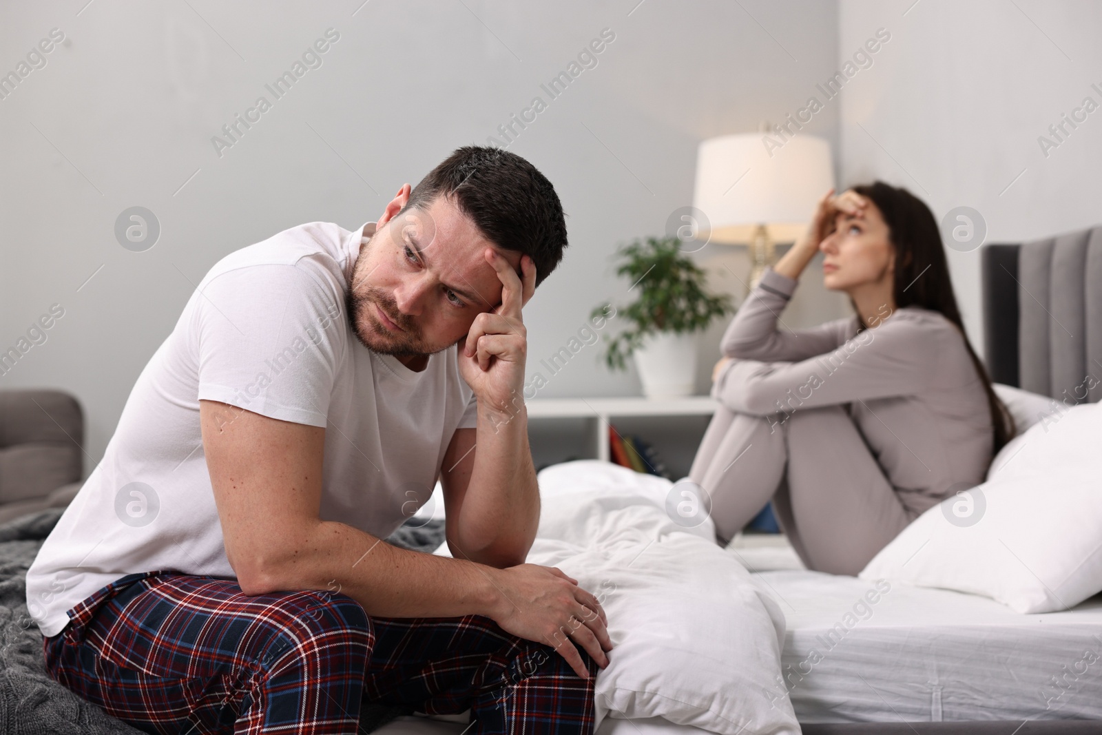 Photo of Offended couple ignoring each other after quarrel in bedroom, selective focus. Relationship problems