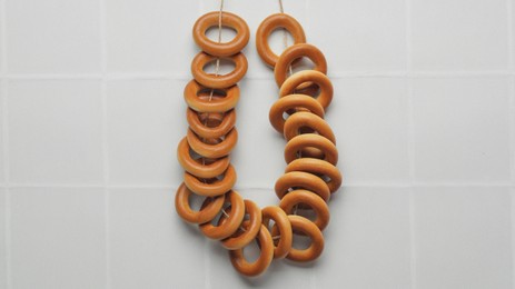 Photo of Bunch of delicious ring shaped Sushki (dry bagels) on white table, top view