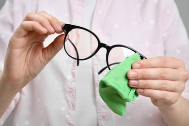 Photo of Woman cleaning glasses with microfiber cloth, closeup