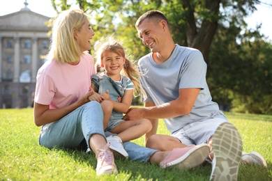 Photo of Happy parents with their child having fun on green grass. Spending time in nature